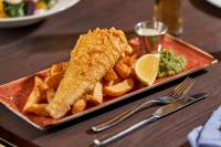 Un plato de comida con pescado y patatas fritas y una lima. en The Cumberland, London, en Londres