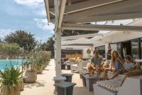 eine Gruppe von Menschen sitzt auf einer Terrasse neben einem Pool in der Unterkunft Slow Village Saint-Martin-de-Ré in Saint-Martin-de-Ré