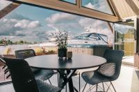 a table and chairs on a balcony with a boat at Ostas Mājas in Engure