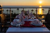 a table with plates and napkins on a balcony with the ocean at Senza Grand Santana Hotel - Ultra All Inclusive in Mahmutlar