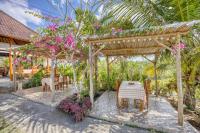 un pergolato in legno con tavoli, sedie e fiori di Bagia Bungalows a Nusa Penida