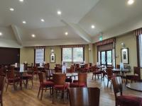 een eetkamer met tafels en stoelen en ramen bij Keer Side Lodge, Luxury lodge with private hot tub at Pine Lake Resort in Carnforth