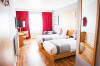 two beds in a hotel room with red curtains at Ramada by Wyndham Belfast in Belfast