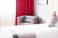 a bedroom with a chair and a red curtain at Ramada by Wyndham Belfast in Belfast