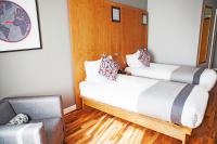 two beds in a room with wood floors and a chair at Ramada by Wyndham Belfast in Belfast