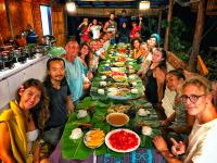 a group of people sitting around a long table of food at Langkawi Country Lodge2 in Pantai Cenang