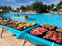 a pool with several tables filled with fruits and vegetables at Bungalow de 3 chambres avec piscine partagee et terrasse a Vias a 1 km de la plage in Vias