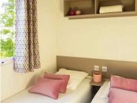 a bed with pink and white pillows and a window at Bungalow de 3 chambres avec piscine partagee et terrasse a Vias a 1 km de la plage in Vias