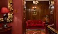 a red chair in a hallway with a red wall at The Rookery in London