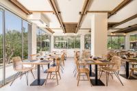 une salle à manger avec tables et chaises et de grandes fenêtres dans l'établissement Luxury Villa Muse Calliope, à Matala