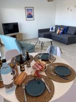a table with plates and wine bottles on it in a living room at Exceptionnelle Vue Mer Calvi - Piscine - T2 in Calvi