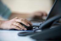 a person typing on a laptop computer with their hand on a mouse at Crowne Plaza Chicago O'Hare Hotel & Conference Center by IHG in Rosemont