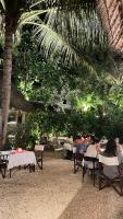 ナングウィにあるAtii Garden Bungalowsのヤシの木の下のテーブルに座っている人々のグループ