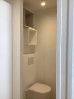 a bathroom with a toilet and shelves on the wall at Beau Duplex Neuf Calme Lumineux 45m2 en plein COEUR de la station à 100m du port sur book ing &amp; rbnb in Bénodet