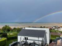 un arc-en-ciel sur un bâtiment blanc avec une maison dans l&#39;établissement Plage du Débarquement. Maison bord de Mer, à Saint-Côme-de-Fresné