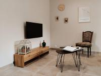 a living room with a television and a table and chairs at Charmante maison avec jardin aux portes des gorges de l&#39;Ardèche in Saint-Julien-de-Peyrolas