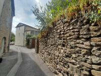 a stone wall next to a street with a building at Gîte Olivia in Saint-Florent-sur-Auzonnet