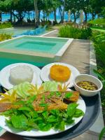 ein Teller mit Essen auf einem Tisch neben einem Pool in der Unterkunft Mahogany Resort & Spa in El Nido