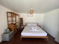 a bedroom with a bed with white sheets and a shelf at Nice Sea Resort in Srithanu