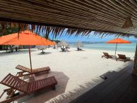 a beach with benches and umbrellas and the ocean at Nice Sea Resort in Srithanu