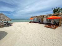 a building on the beach with umbrellas and the ocean at Nice Sea Resort in Srithanu
