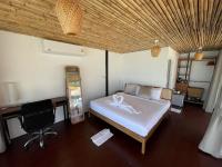 a bedroom with a bed and a desk and a chair at Nice Sea Resort in Srithanu
