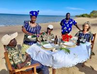 Un grupo de personas sentadas en una mesa en la playa. en Villa Moringa Lodge, en Lumbo