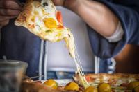 a person is holding a slice of pizza at Hotel Residence Loren - contact & contactless check-in in Uster