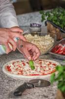 a person making a pizza on a counter at Hotel Residence Loren - contact & contactless check-in in Uster