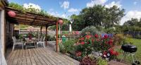 a wooden deck with a table and chairs and flowers at MAISON &amp; PISCINE PRIVES,PLAGES OCEAN ET LAC A 10 kms in Linxe