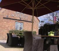 a table with an umbrella in front of a building at Landhaus Jenischpark in Hamburg