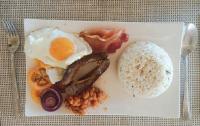 Un plato de desayuno con huevo, tocino, frijoles y arroz. en Palawan SandCastles, en Minuit