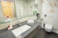 a bathroom with a sink and a toilet and a mirror at Austria Trend Hotel Congress Innsbruck in Innsbruck