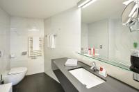 a bathroom with a sink and a toilet and a mirror at Austria Trend Hotel Congress Innsbruck in Innsbruck
