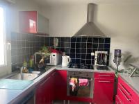 a kitchen with red cabinets and a stove top oven at Agréables chambres dans maison suspendue in Saint-Étienne