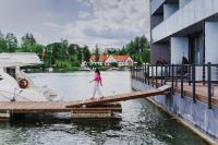 a girl walking on a dock next to a boat at Hotel Mikołajki Leisure &amp; SPA in Mikołajki