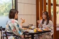 dos mujeres sentadas en una mesa comiendo comida en KAMENOI HOTEL Okunikko, en Nikko