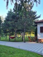 a hammock in a park with trees and a building at Kuća za odmor Čanić gaj in Gospić