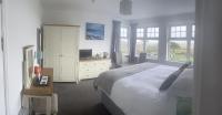 a bedroom with a bed and a desk with a television at Beacon Country House Hotel &amp; Luxury Shepherd Huts in St. Agnes
