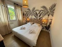 a bedroom with a large white bed with two flowers on it at « L’Hilo » Appart 4 Personnes À 250 m de la Plage in Varaville