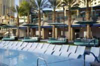 ein Pool mit Stühlen und Sonnenschirmen und Palmen in der Unterkunft Hilton Club Elara Las Vegas in Las Vegas
