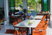 een restaurant met tafels, stoelen en ramen bij VeeVaree Riverkwai Resort in Ban Kaeng Raboet
