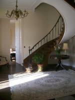 a living room with a staircase with a table and a rug at Manoir Angle in Blanzay-sur-Boutonne