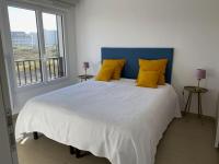 a bedroom with a large bed with yellow pillows at Appartement cosy proche de la mer in Neufchâtel-Hardelot