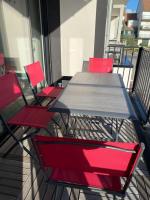 a table and four red chairs on a balcony at Appartement cosy proche de la mer in Neufchâtel-Hardelot