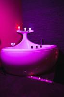 a white sink in a room with a pink light at HomeSparadise Loveroom in Besançon