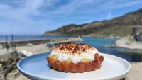 a pastry on a white plate with a view of the beach at Hôtel de la jetée in Centuri