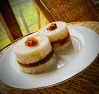 Dos trozos de pastel en un plato blanco sobre una mesa. en Sigiri Holiday Bungalow, en Sigiriya