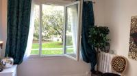 a window with green curtains and a plant in a room at La chambre de Lou in Chatou