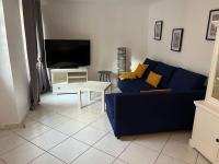 a living room with a blue couch and a tv at Petite maison de ville au calme in Brie-Comte-Robert
